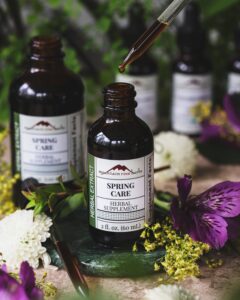 Mountain Rose Herbs Spring Care herbal tincture bottle with dropper and flowers, featuring seasonal support blend for overall wellness.