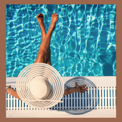 Overhead view of summer poolside with straw hat, sunglasses, and clear blue water. Clean summer lifestyle photo.