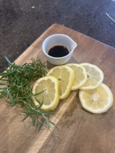 resh rosemary, lemon slices, and vanilla extract on a wooden cutting board – ingredients for a non-toxic summer simmer pot.